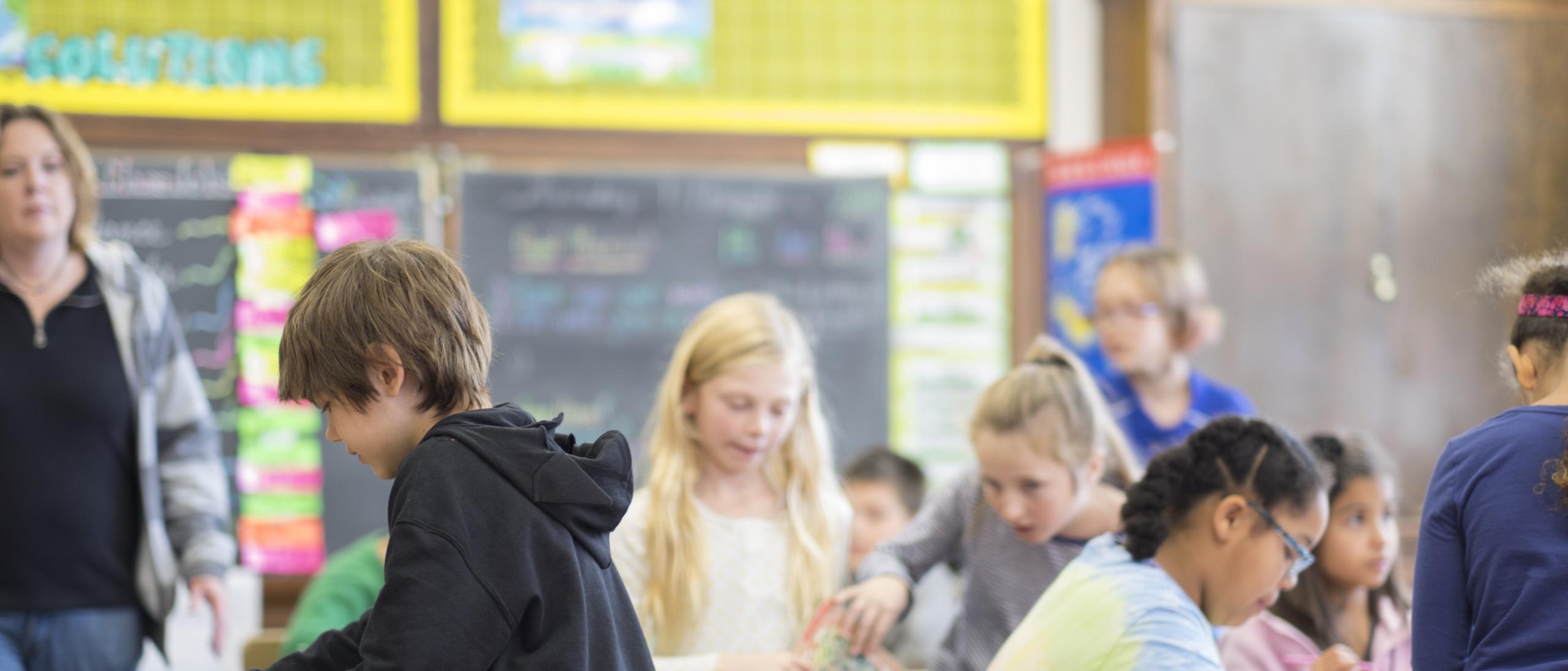 Young students in classroom with teacher in the background